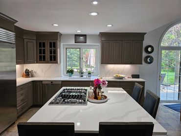 Modern kitchen with white marble countertops and brown cabinets.