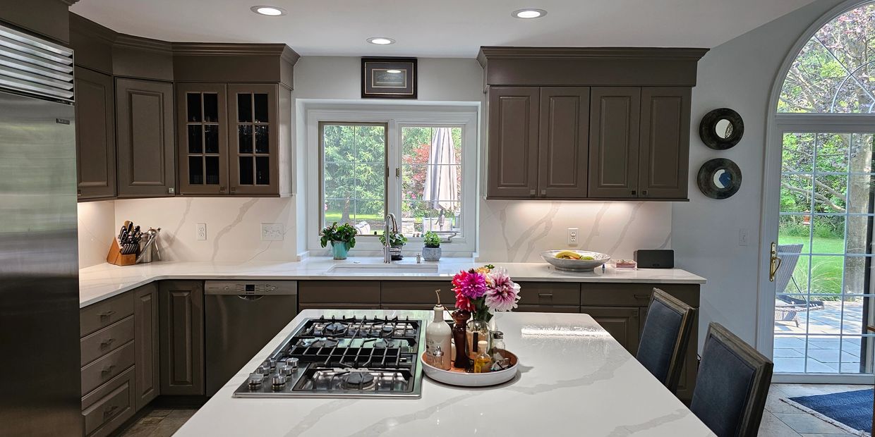 Modern kitchen with white marble countertops and brown cabinets.