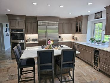 Modern kitchen with gray cabinets, marble countertops, and an island with bar stools.