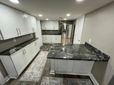 Modern kitchen with white cabinets and dark patterned granite countertops.
