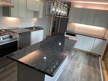 Modern kitchen with black granite countertops and white cabinetry under soft lighting.
