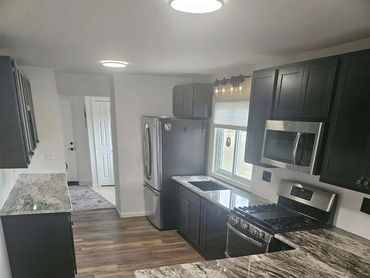 Modern kitchen with dark cabinets and marble countertops.