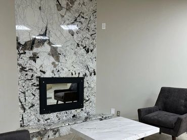 Modern sitting area with gray chairs and marble table by patterned wall.