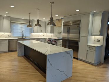 Modern kitchen with marble island and stainless steel appliances.