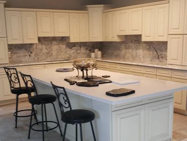 Spacious kitchen with large island and black cushioned bar stools.