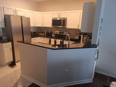 Modern kitchen with white cabinets and black granite countertops.
