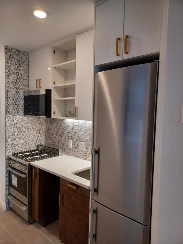 Modern kitchen with stainless steel appliances and mosaic backsplash.