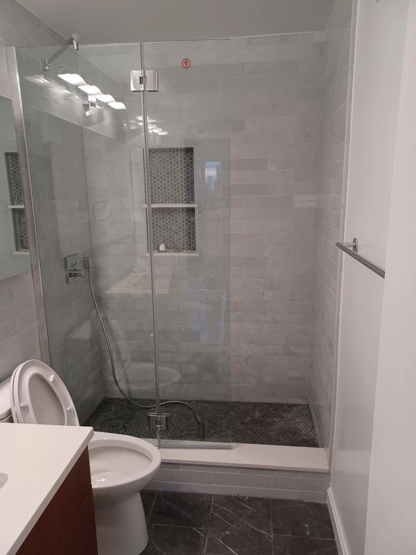 Modern bathroom with glass shower and white tiles.