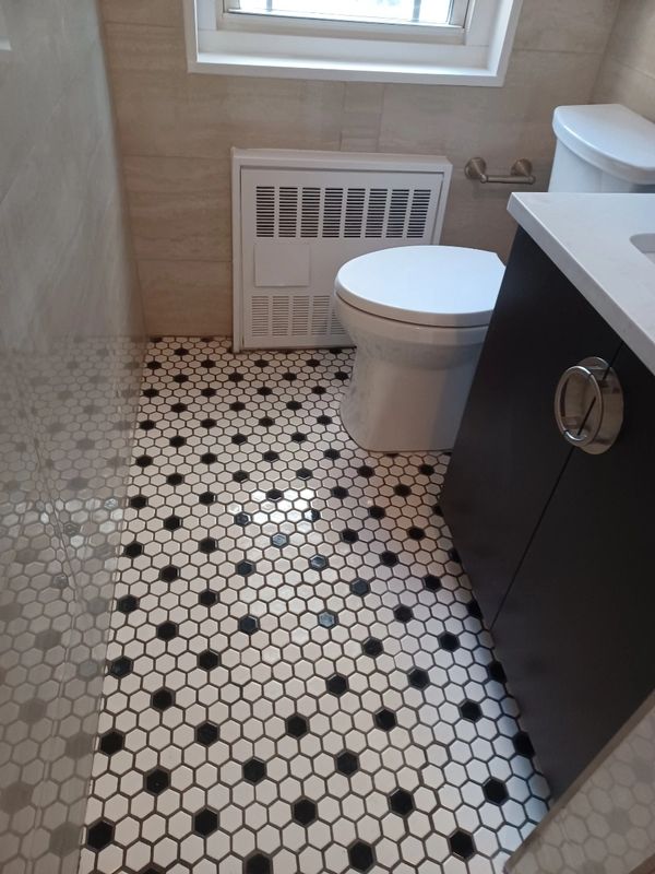 Small bathroom with black and white hexagonal tiled floor and modern fixtures.