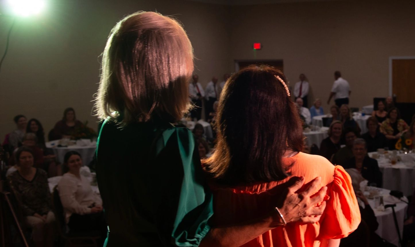 Mary and her mother face audience as we see them from the back.