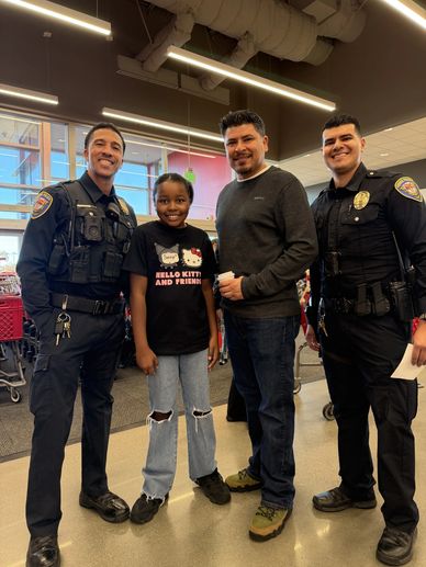 Two police officers and two civilians smiling inside a store.