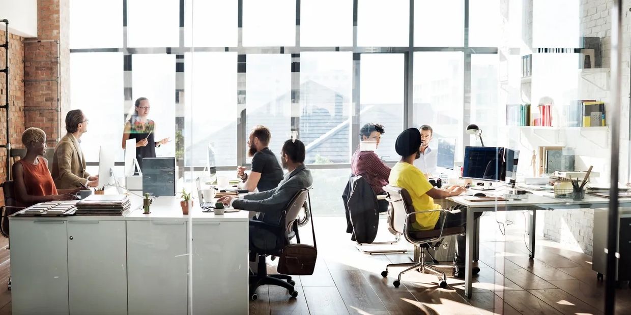 Team collaborating in a bright, modern office with large windows.