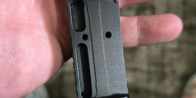 Close-up of a person's hand holding a metal firearm magazine.