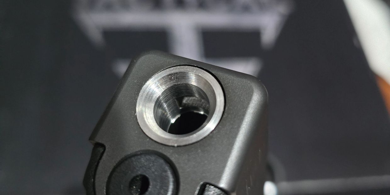 Close-up of a metallic circular opening on a black object.