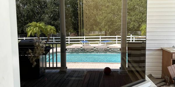 Reflection of a covered patio and pool in a large window.