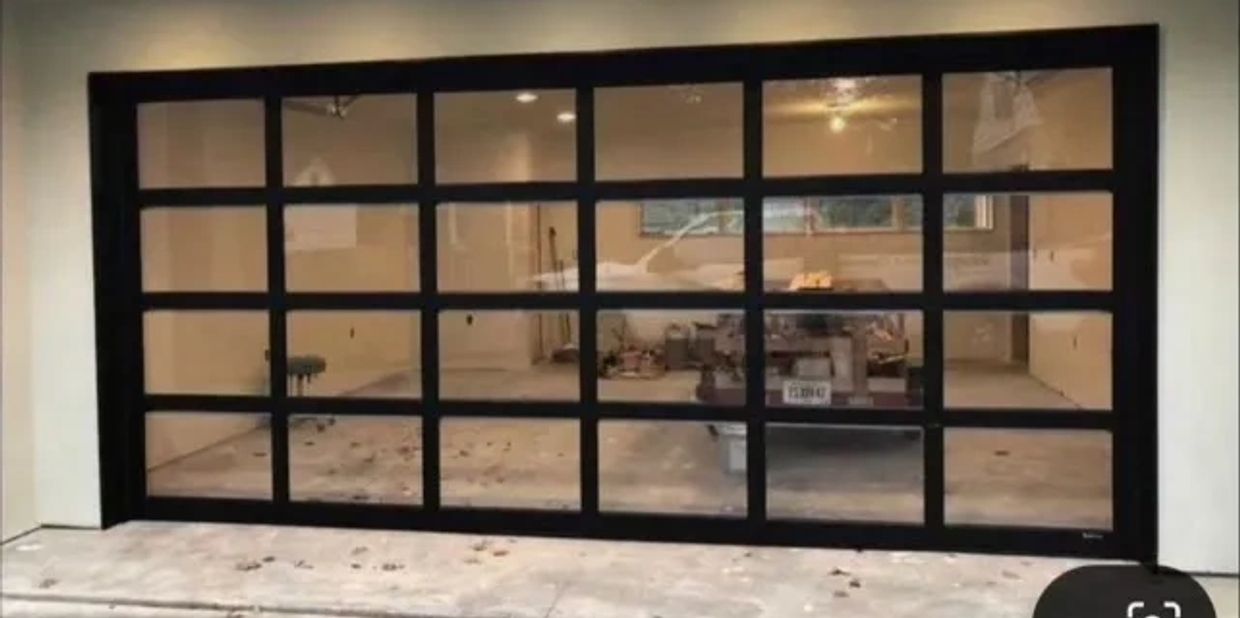 Modern glass garage door with black frames revealing a cluttered interior.