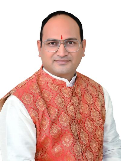 Man wearing traditional Indian attire with glasses and a red tilak on forehead.