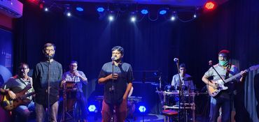 Band performing on stage under blue and red lights.