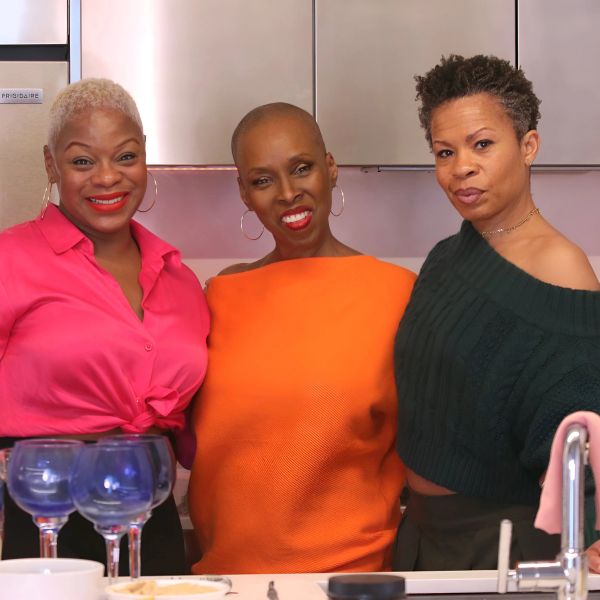 Three women smiling together in a kitchen.