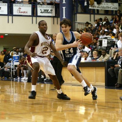 High school basketball game with player dribbling past defender.