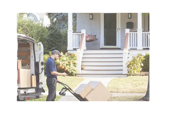 Delivery person with hand truck unloading boxes at a house porch.