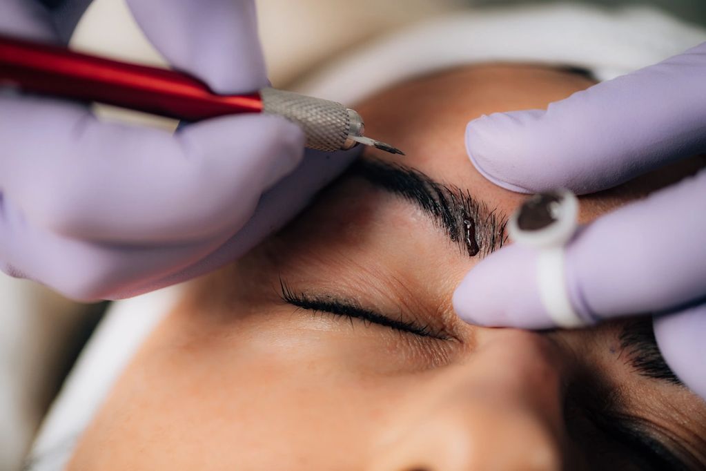 Applying microblading ink to patient's eyebrows
