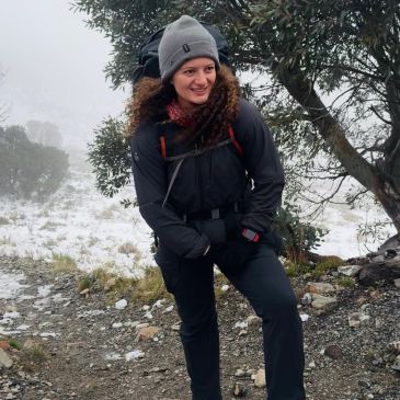 Person hiking in snowy, foggy forest.