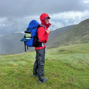 Hiker with a large blue backpack on a misty mountain trail.