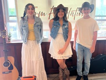 Three kids dressed in casual Western-style clothing indoors.