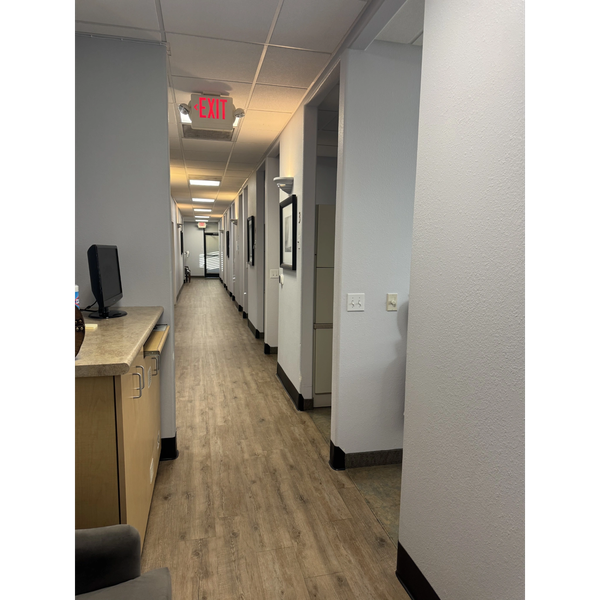 Empty office hallway with wooden flooring and exit signs.
