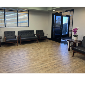 A clean and modern waiting room with black chairs and potted orchids.