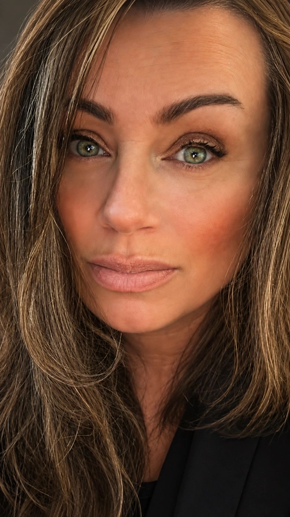 Close-up of a woman with green eyes and long hair.