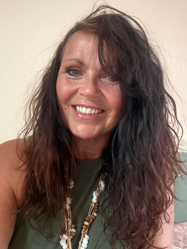 Smiling woman with long wavy hair and necklace.