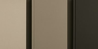 Three closed hardcover books in neutral shades arranged side by side.