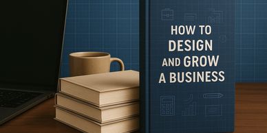A business book titled 'How to Design and Grow a Business' on a desk with a laptop and coffee.