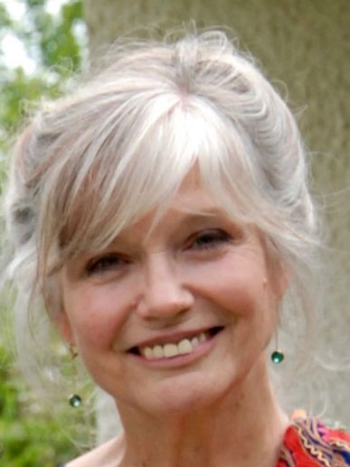 Front angle view of a lady with white hairs smiling at the camera