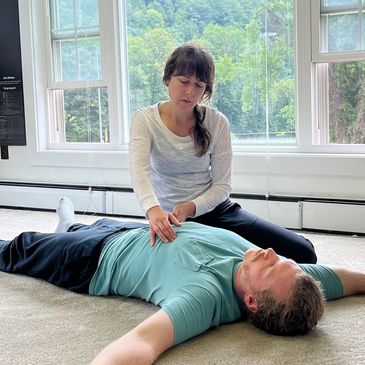 A girl helping a man while exercise inside a room