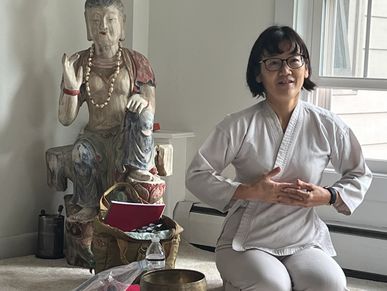 An old lady sitting on the floor along with a idol