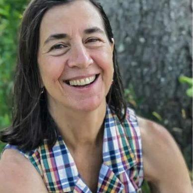 Front angle view of a small lady with black hairs smiling at the camera