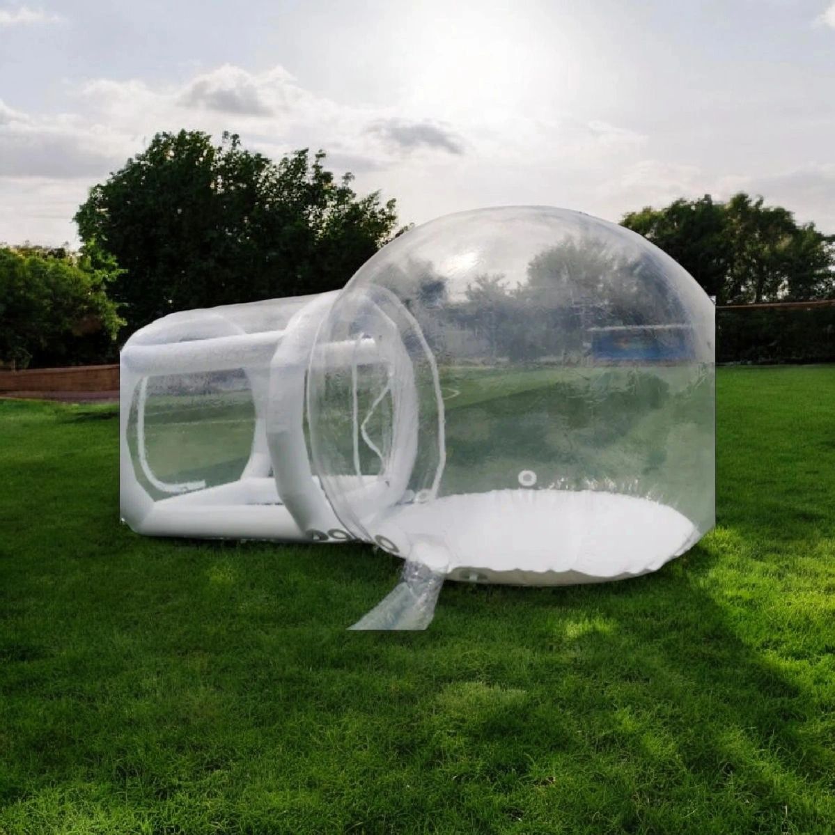 Transparent inflatable outdoor bubble tent on green grass.