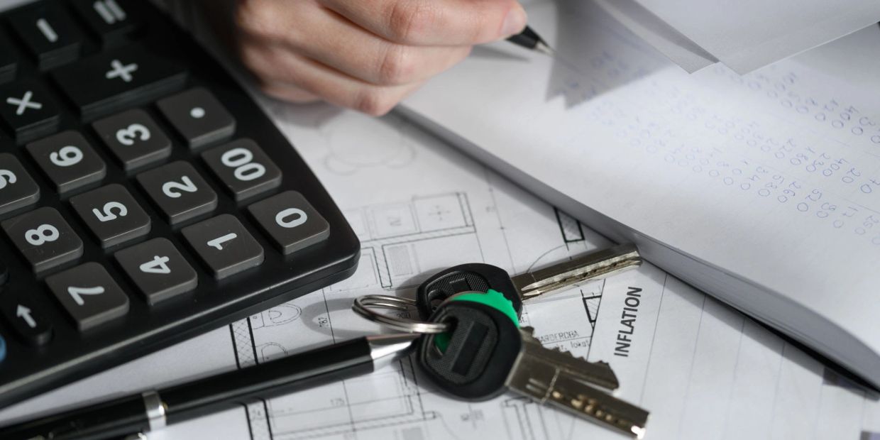 Calculator, keys, pen, and documents on a desk focused on inflation.