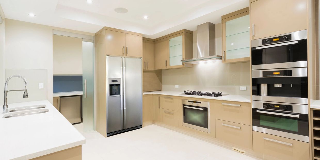 Modern kitchen with beige cabinets and stainless steel appliances.