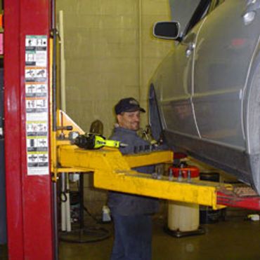 Technician working on a car on a yellow lift