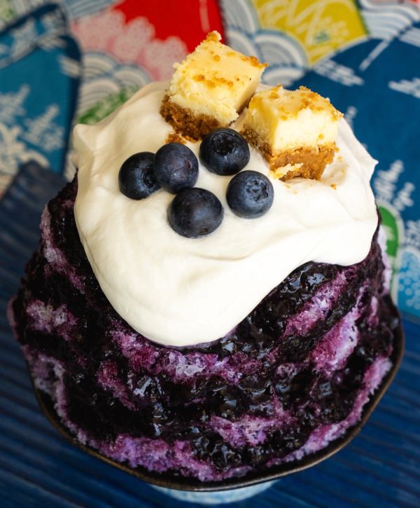 Blueberry shaved ice topped with cream, fresh blueberries, and cheesecake bites.