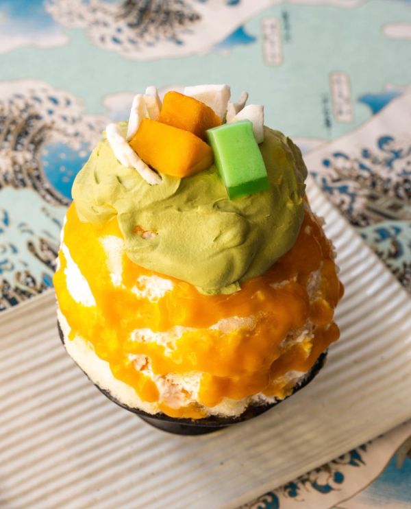 Colorful shaved ice dessert with green, yellow, and white toppings.
