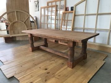 Wooden table on wooden floor with window frames in background.