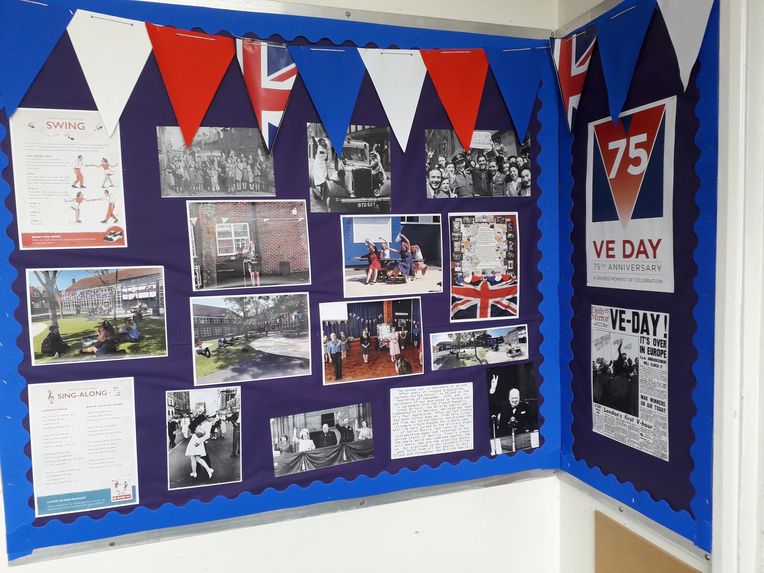 A VE Day 75th Anniversary display with historical photos and Union Jack bunting on a blue board.