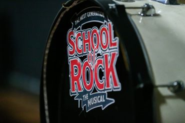 Close-up of a white bass drum featuring the "School of Rock The Musical" logo in red and black