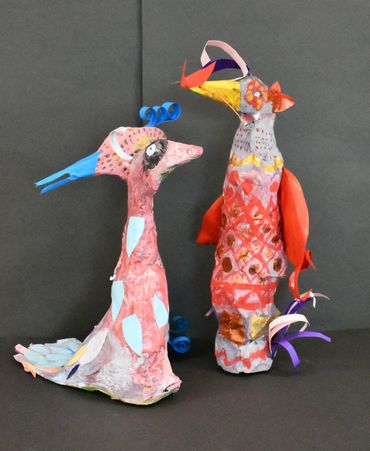 Two paper-mâché bird sculptures with colourful patterns and paper crests