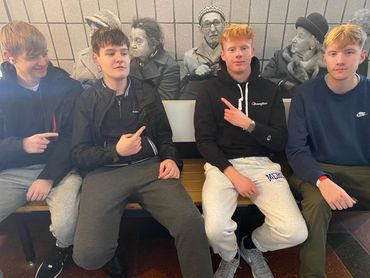 Students on a bench by a black and white tiled mural, Berlin trip